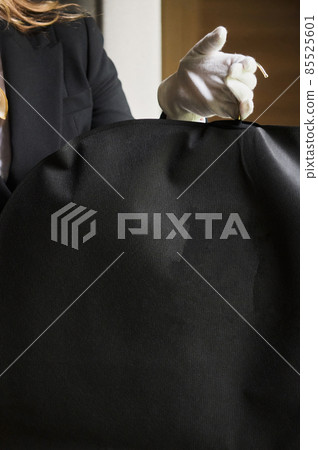 Black garment, suit travel bag. the hands of a hotel worker in white gloves. Black garment, suit travel bag. the hands of a hotel worker in white gloves. 85525601