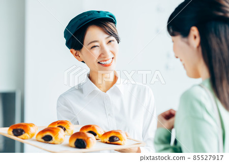 A middle-aged female clerk who promotes freshly baked bread to customers A middle-aged female clerk who promotes freshly baked bread to customers 85527917
