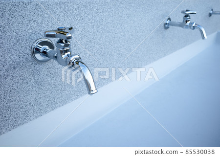 Water faucets lined up with outdoor drinking fountains 85530038