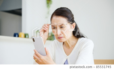 Senior woman with presbyopia looking at a smartphone Senior woman with presbyopia looking at a smartphone 85531745