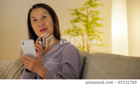 晚上在客廳裡用智能手機的老婦人 85532789