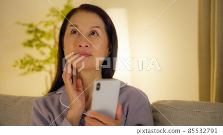 晚上在客廳裡用智能手機的老婦人 晚上在客廳裡用智能手機的老婦人 85532791