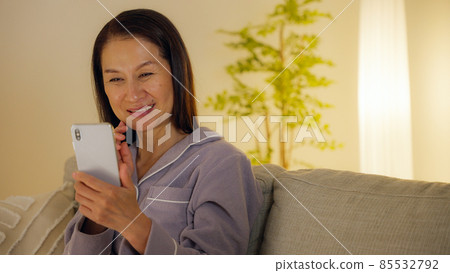 晚上在客廳裡用智能手機的老婦人 85532792