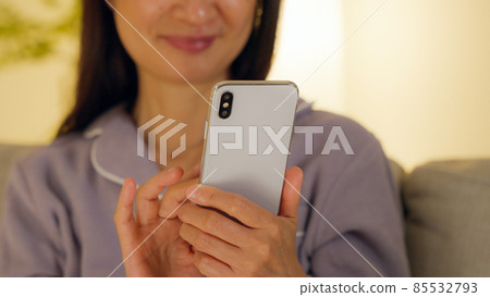 晚上在客廳裡用智能手機的老婦人 85532793