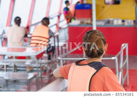 Back view of Asian woman in life vest relaxing on balcony enjoying view from boat of Samui island in the sea. Happy casual female tourists outside on tropical holiday destination.Cruise ship vacation. Back view of Asian woman in life vest relaxing on balcony enjoying view from boat of Samui island in the sea. Happy casual female tourists outside on tropical holiday destination.Cruise ship vacation. 85534161