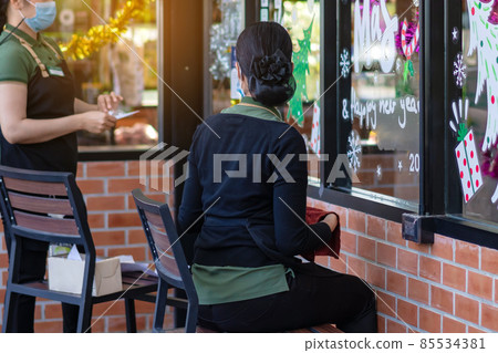 Asian women decorate beautiful stickers on window glass in front of cafe to welcome Christmas and New Year. Prepare to decorate the storefront to be beautiful during the important holidays of year. Asian women decorate beautiful stickers on window glass in front of cafe to welcome Christmas and New Year. Prepare to decorate the storefront to be beautiful during the important holidays of year. 85534381