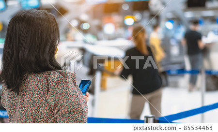 Back view of airline passenger wear face mask to prevent Corona virus (Covid-19) wait to check in counter in airport with staff wear face mask. New normal concept of travel after Covid-19 pandemic. 85534463