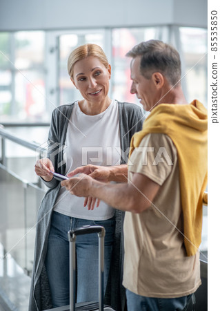 Female passenger and her travel companion talking at the airport Female passenger and her travel companion talking at the airport 85535850