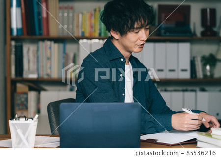 A man writing in front of a computer A man writing in front of a computer 85536216