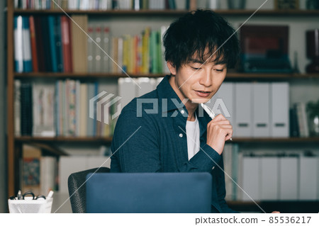 A man writing in front of a computer A man writing in front of a computer 85536217