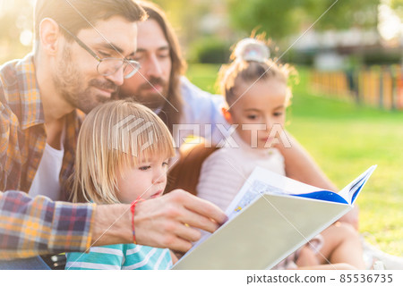 gay male couple with children reading a children's book. 85536735