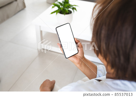 Senior woman using smart phone with copy space in living room at home 85537013