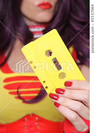 Yellow Cassette Tape With Woman in Retro clothing in background 85537064