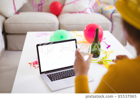 Senior woman video calling through laptop while enjoying champagne during party at home, copy space Senior woman video calling through laptop while enjoying champagne during party at home, copy space 85537065