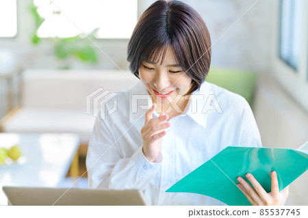 一位從事遠程辦公的年輕女商人在客廳裡與文件聊天時解釋 一位從事遠程辦公的年輕女商人在客廳裡與文件聊天時解釋 85537745