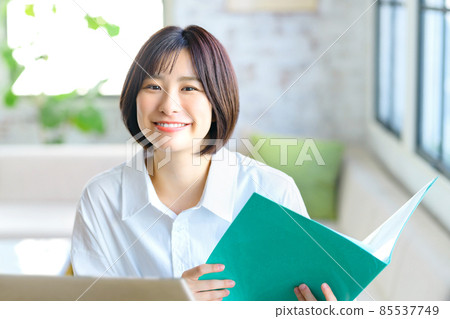 A young business woman in telework explaining in a chat with a document in her living room A young business woman in telework explaining in a chat with a document in her living room 85537749