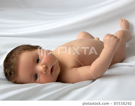Newborn baby in a wrap on white blanket. Beautiful 85538292