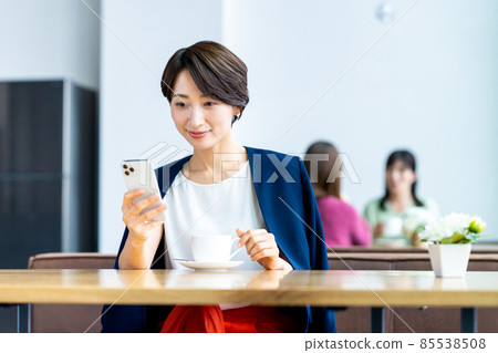 在咖啡館看智能手機的中年婦女 在咖啡館看智能手機的中年婦女 85538508