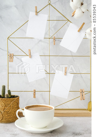 White home office room interior, bloggers workplace. Cup of coffee. Mood board with postcards and reminders mockup. Cotton branches in a vase, interior decoration. Freelance workplace 85539343