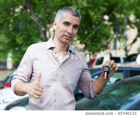 Portrait of male who is standing satisfied with key near his car 85540113