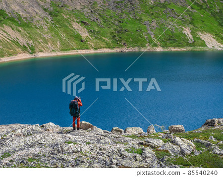 Travel photographer take a picture of the distant mountain turquoise lake from high mountains.Travel freelancer blogger lifestyle, concept adventure voyage outdoor. 85540240