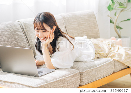 一個女人躺在沙發上時使用計算機 85540617