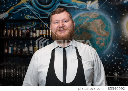 Bearded Adult Funny Positive Smiling Caucasian Looking Professional Bartender Portrait in Nightclub Bearded Adult Funny Positive Smiling Caucasian Looking Professional Bartender Portrait in Nightclub 85540992