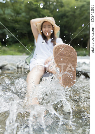 A girl playing with water splashes in the river A girl playing with water splashes in the river 85541893