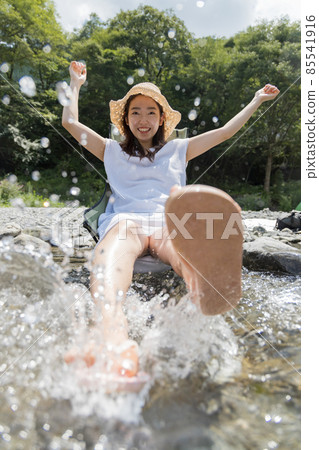 A girl playing with water splashes in the river 85541916