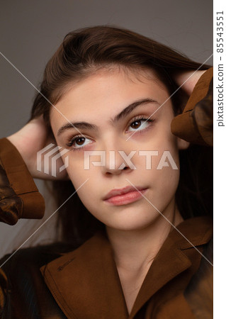 Dark hair young woman with dark grey wall behind Dark hair young woman with dark grey wall behind 85543551