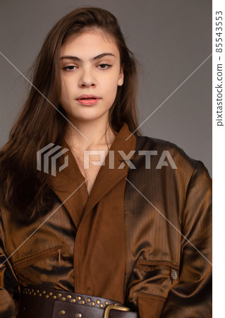 Dark hair young woman with dark grey wall behind Dark hair young woman with dark grey wall behind 85543553