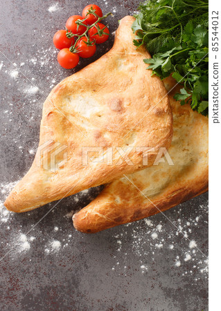 Shotis puri or simply shoti is a type of traditional Georgian bread made of white flour and shaped like a canoe close up. Vertical top view Shotis puri or simply shoti is a type of traditional Georgian bread made of white flour and shaped like a canoe close up. Vertical top view 85544012