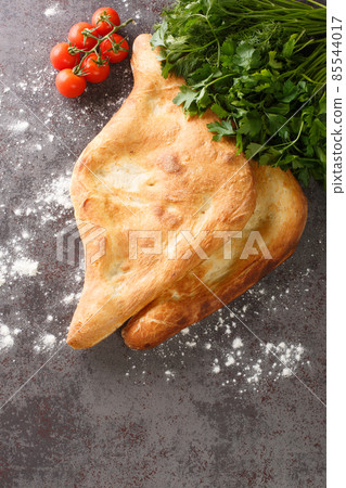 Shotis puri or shoti is a Georgian bread made with whole wheat flour, salt, water, and yeast close up. Vertical top view Shotis puri or shoti is a Georgian bread made with whole wheat flour, salt, water, and yeast close up. Vertical top view 85544017