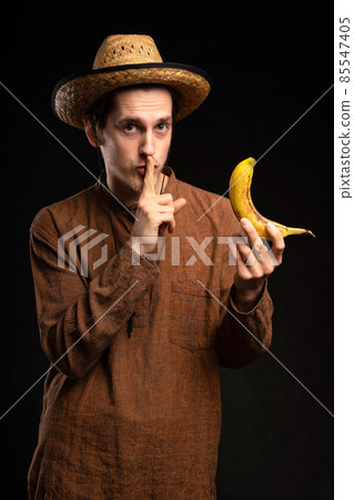 Young man with banana on black Young man with banana on black 85547405