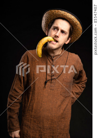 Young man with banana on black Young man with banana on black 85547407