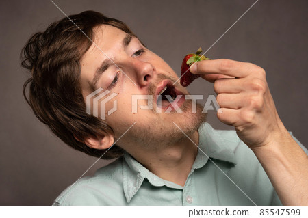 Young man with strawberries on grey Young man with strawberries on grey 85547599