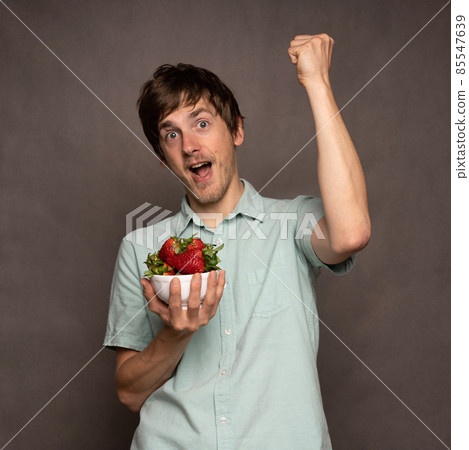 Young man with strawberries on grey Young man with strawberries on grey 85547639