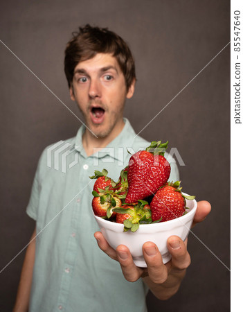 Young man with strawberries on grey Young man with strawberries on grey 85547640