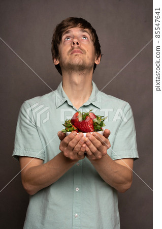 Young man with strawberries on grey 85547641