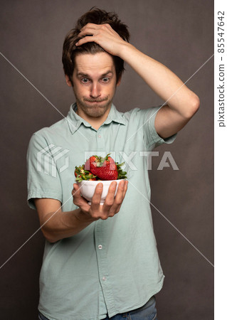 Young man with strawberries on grey Young man with strawberries on grey 85547642