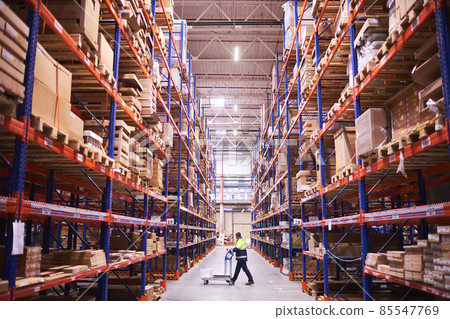 Male warehouse worker pulling a pallet truck. Male warehouse worker pulling a pallet truck. 85547769