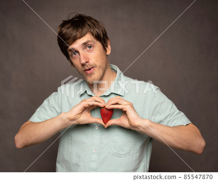Young man with strawberry on grey Young man with strawberry on grey 85547870