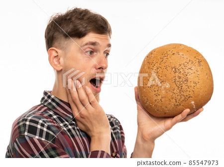 Young man with loaf of bread on white Young man with loaf of bread on white 85547973