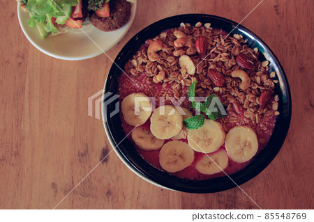Top view of a healthy vegan smoothie bowl made of red dragon fruit, bananas with oats cashew nuts and almonds Top view of a healthy vegan smoothie bowl made of red dragon fruit, bananas with oats cashew nuts and almonds 85548769