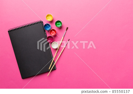 Album pages and paints, pencils, brush on a colored background. Top view with empty space. workplace for creativity. home teaching concept drawing Album pages and paints, pencils, brush on a colored background. Top view with empty space. workplace for creativity. home teaching concept drawing 85550137