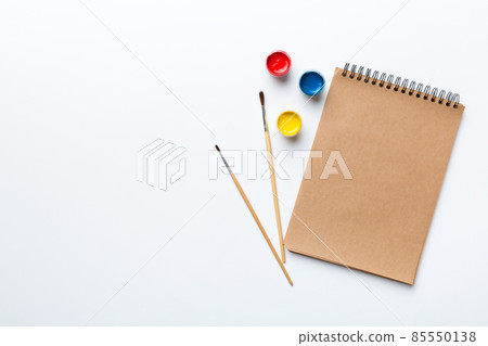Album pages and paints, pencils, brush on a colored background. Top view with empty space. workplace for creativity. home teaching concept drawing Album pages and paints, pencils, brush on a colored background. Top view with empty space. workplace for creativity. home teaching concept drawing 85550138