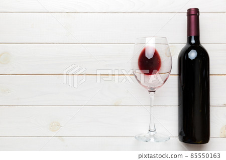 Glass of red wine and a bottle on colored table. Flat lay, top view wth copy space 85550163