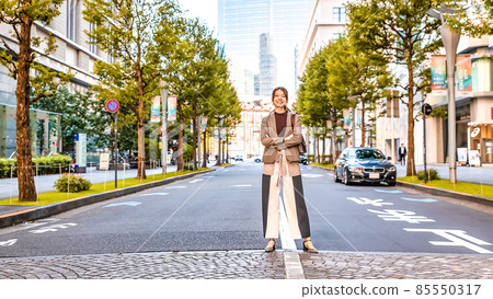 A young woman standing on the Tokyo Maru pedestrian crossing with a smile 85550317