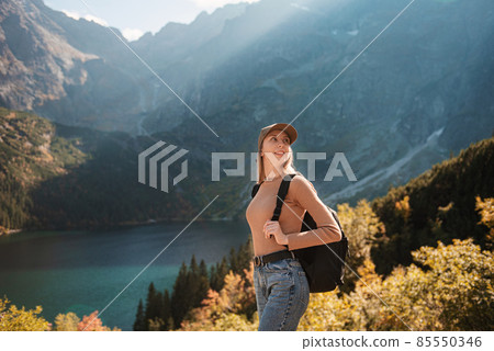 Wanderlust and travel concept. Stylish traveler girl in hat looking at map, exploring woods. 85550346