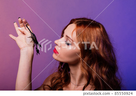 Beautiful seductive fashion redhead female with make up with a scorpion in studio 85550924